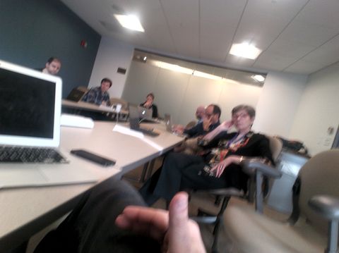 A group of people in an indoor office or classroom space with computers and tables.
