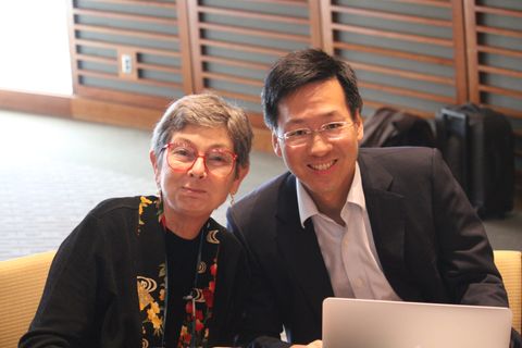 two people sitting at a table with a laptop