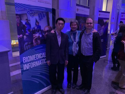 three people posing at a biomedical informatics event indoors