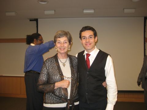 two people posing indoors in front of a projection screen