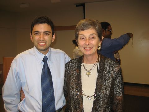 a man in a tie and an older woman pose together indoors at an event