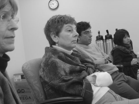 a group of people sitting in a waiting room with a clock on the wall
